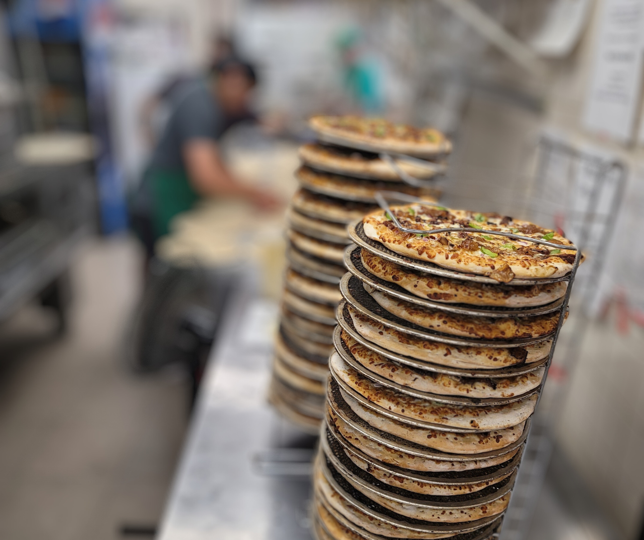 Stacks of fresh pizzas being prepared in the Eat Local Pizza kitchen
